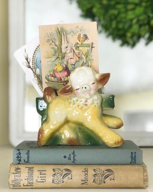A sweet pastel lamb on books holds Easter-related cards.
