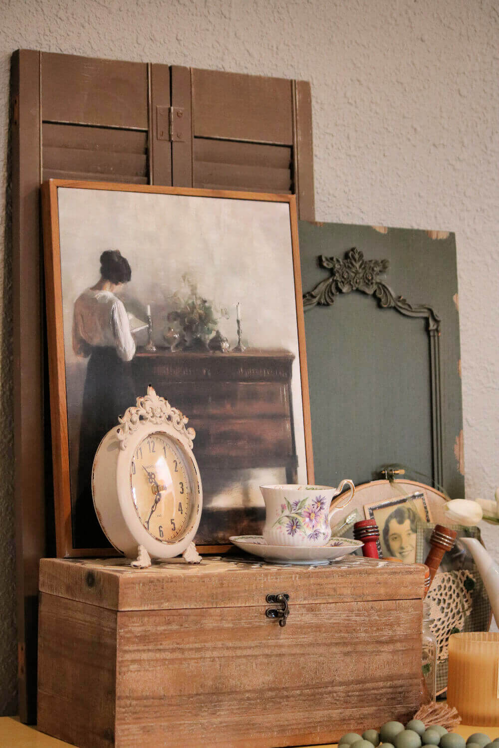 A yellow table with various decor, such as wall decor and a painting, along with a vintage clock and other vintage decor in my living room.