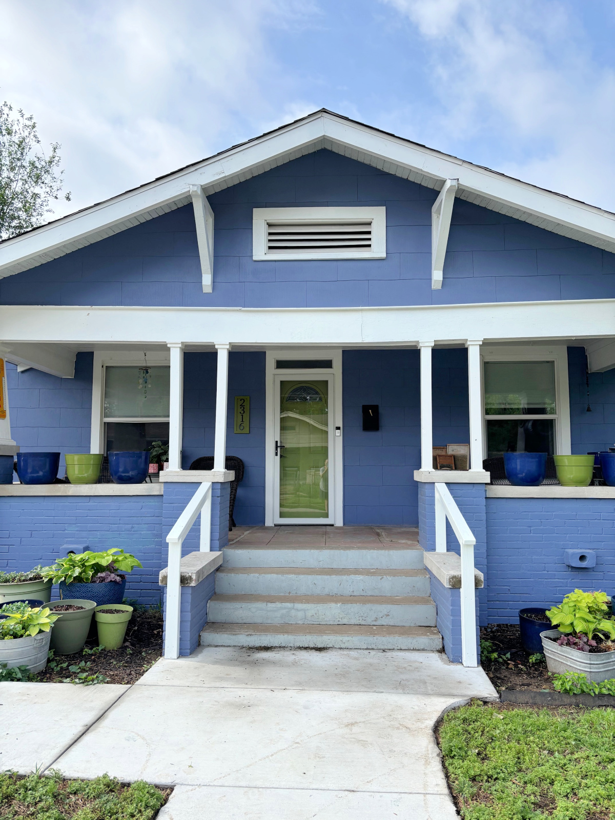 The porch rails have been painted white, and the white storm door was installed.