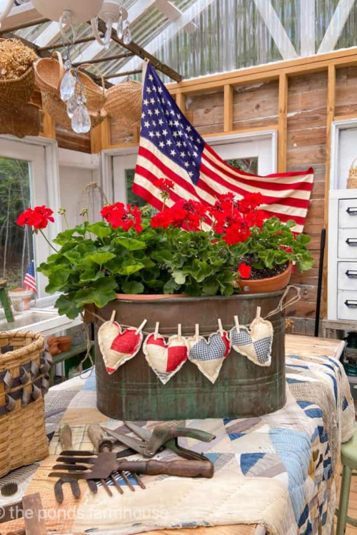 Simple 4th of July porch ideas is red geraniums in a tub with patchwork hearts.