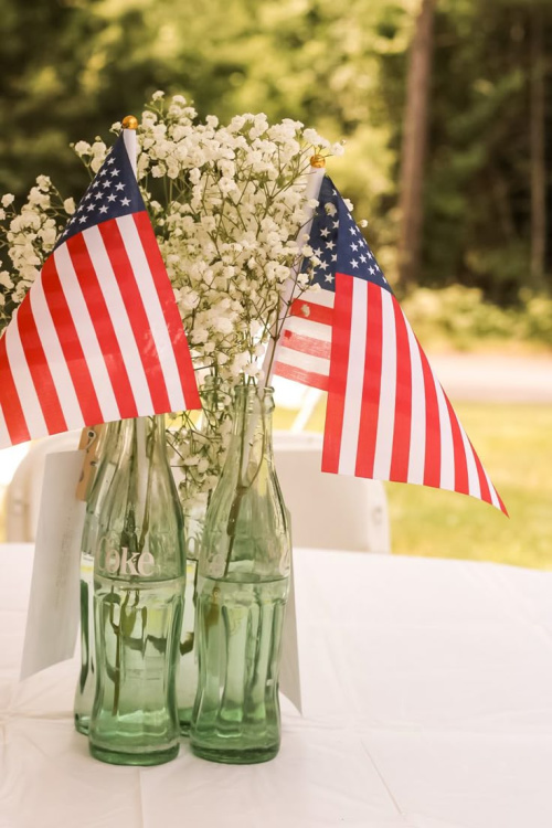 Vintage coca-cola bottles with baby's breath flowers and small flags.