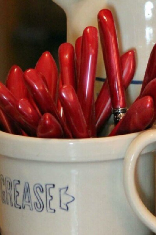 Red handled silverware in a crock. 