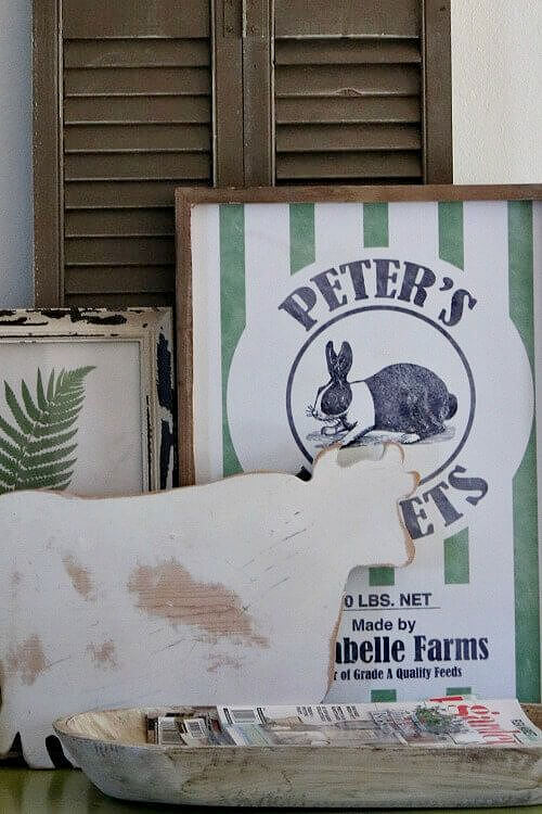 Put decorative vignettes on display by layering wall decor, such as these paintings and a wooden cow shape.