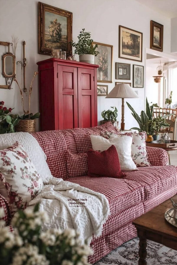 A red and white checked couch is beautiful in front of a red cupboard.