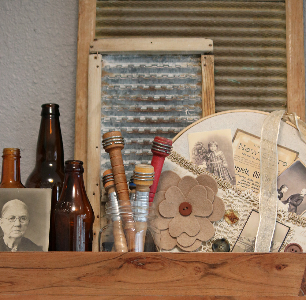 A wooden tray with finds like antique photos, bobbins, brown bottles and DIY embroidery hoop art.