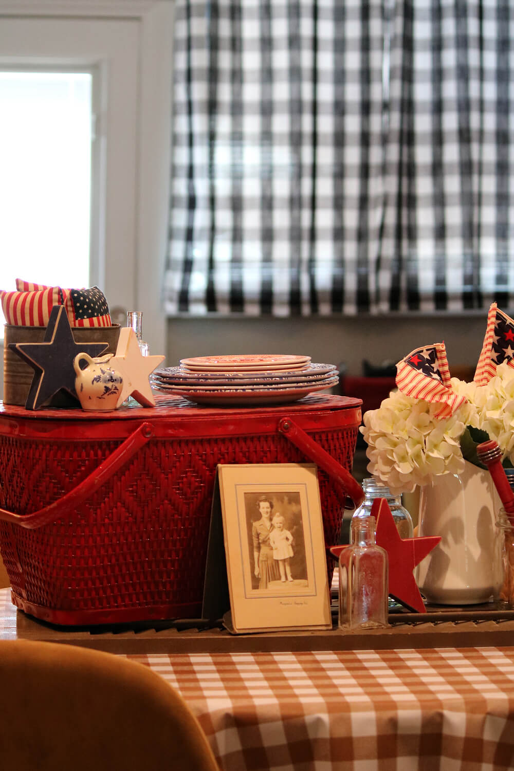 Celebrate July 4th with cozy cottage charm with vintage photos, a red picnic basket, and other red, white, and blue decor.