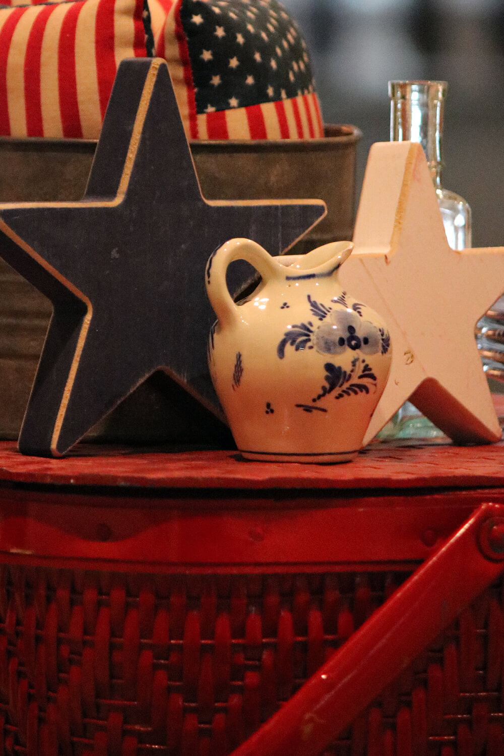 Picnic basket with wooden stars and a small blue and white pitcher.