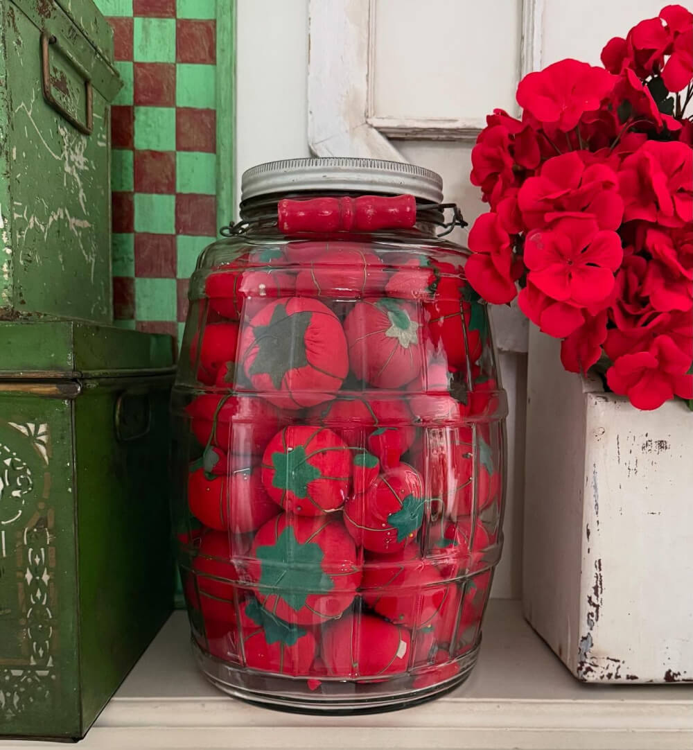 Adding the Tomatocore Aesthetic to Your Home isn't about the color red, it's a lifestyle. Pictured here is a large jar with sewing tomato pin cushions.
