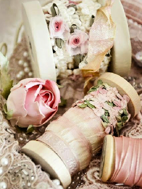 Lacy pink trim around wooden spools.