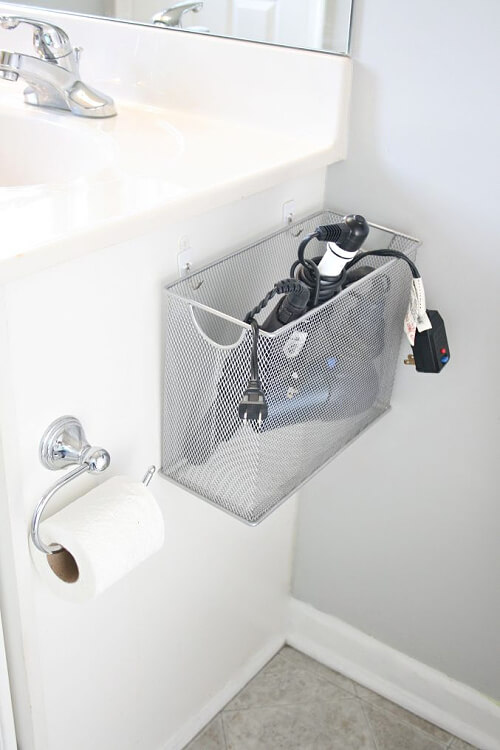 Use adhesive hooks to hang a wire box to the wall for hair dryers.