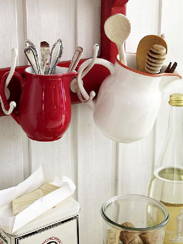 Hooks hold small pitchers that hold various kitchen items like silverware.