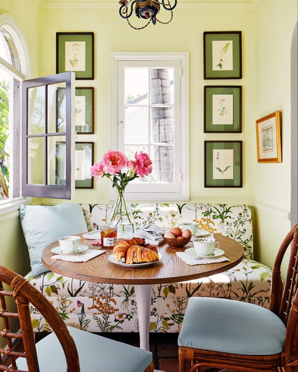 How to create a cozy breakfast nook with this floral love seat, a round wooden table, and two wooden brown chairs with light blue cushions.