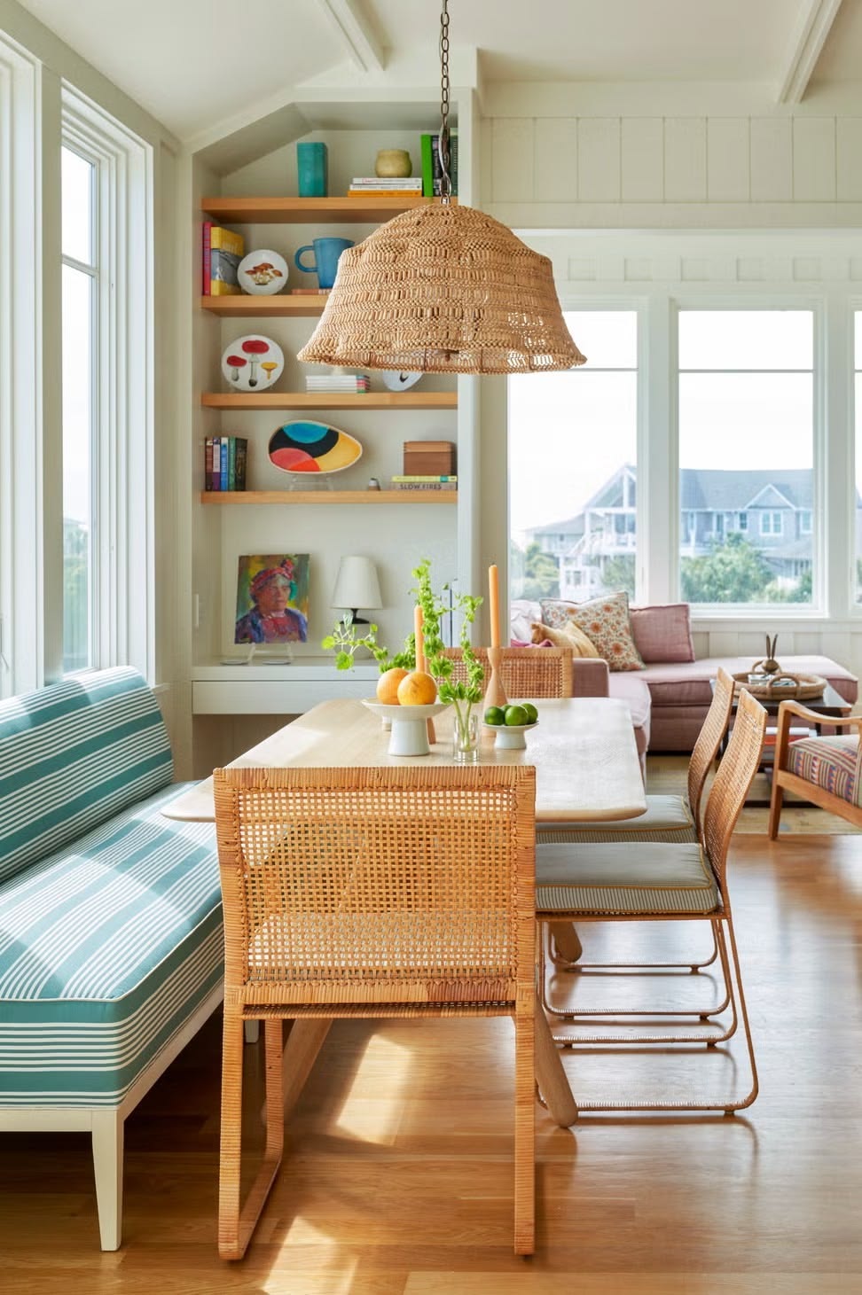 How to create a cozy breakfast nook with a green striped upholstered bench, a rectangular wood table, and four wicker cane chairs.