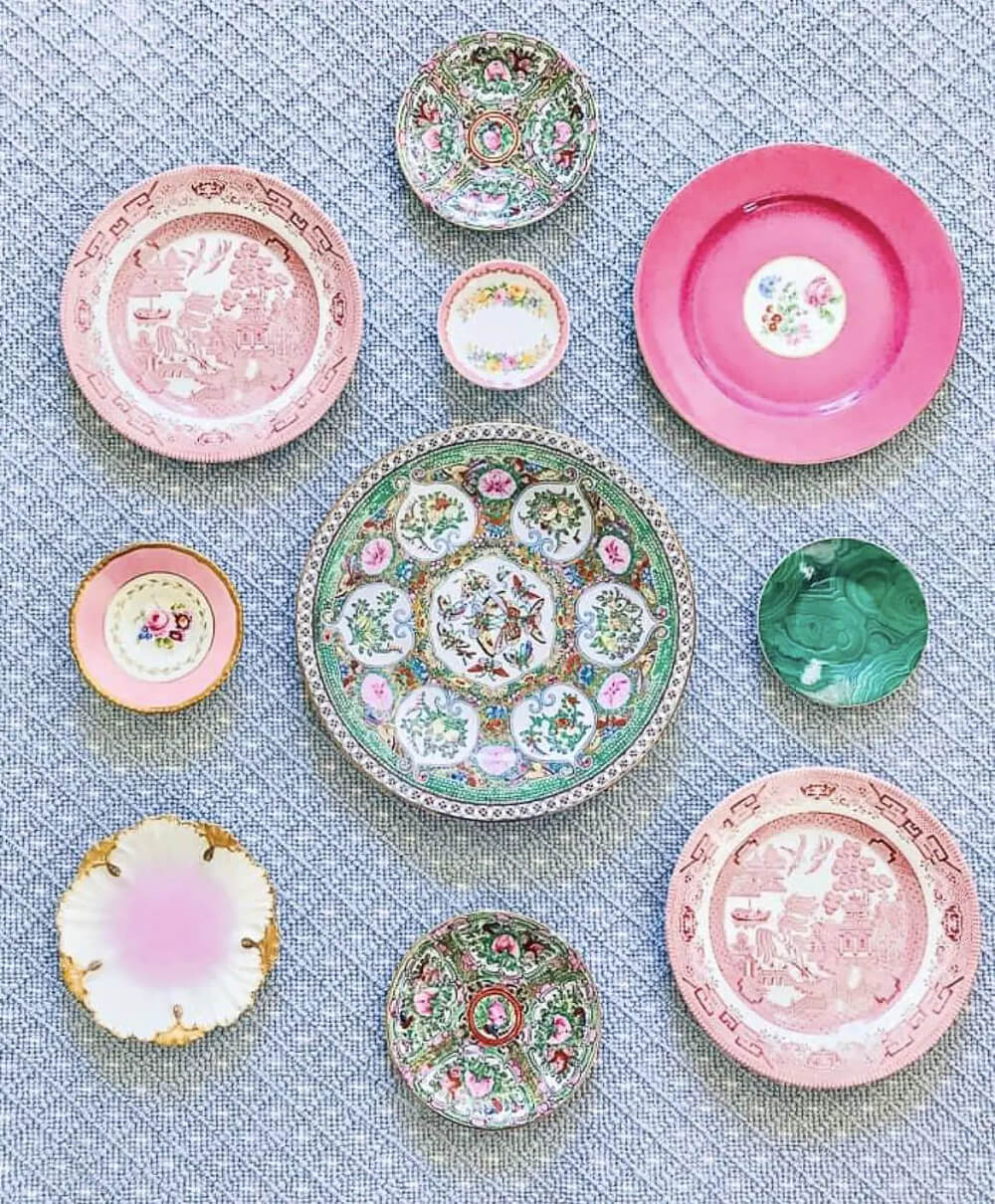 A blue textured wallpapered wall with pink, green, and white plates.