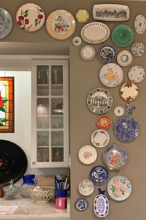 An irregular-shaped wall of various colored plates arcing over a doorway.