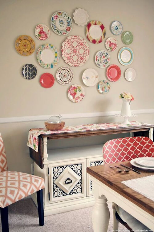 This wall display is irregular above a white credenza covered with a piece of fabric.