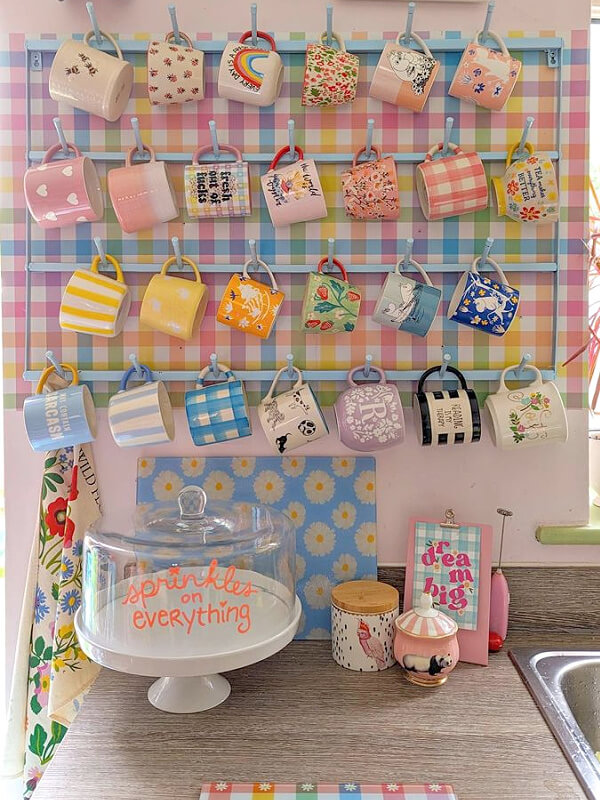 25 clever ways to display coffee mugs include this wall display with pastel wallpaper.