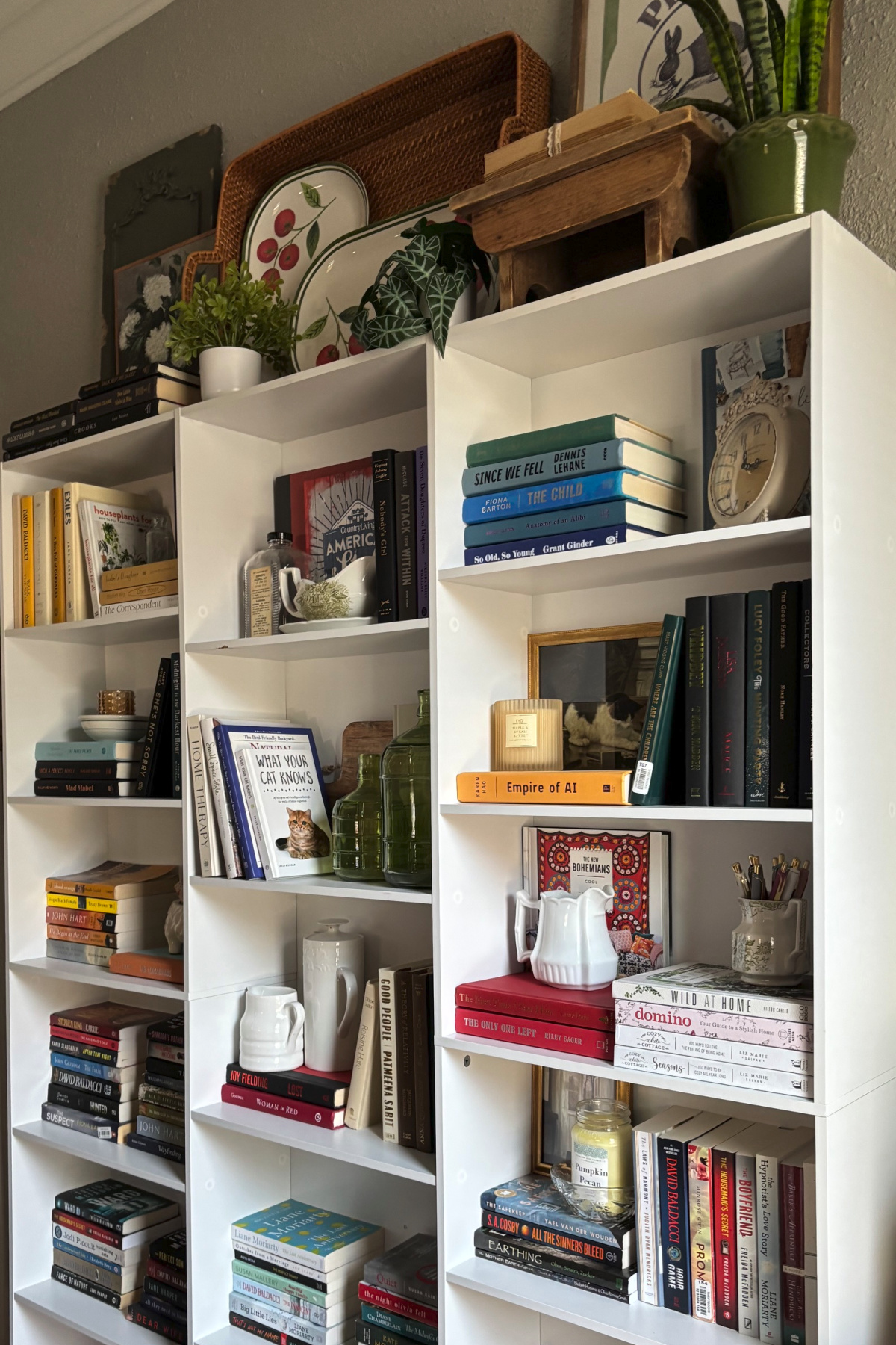 An angled view of my white bookshelves along one living room wall. On top of the shelves I added different decor.