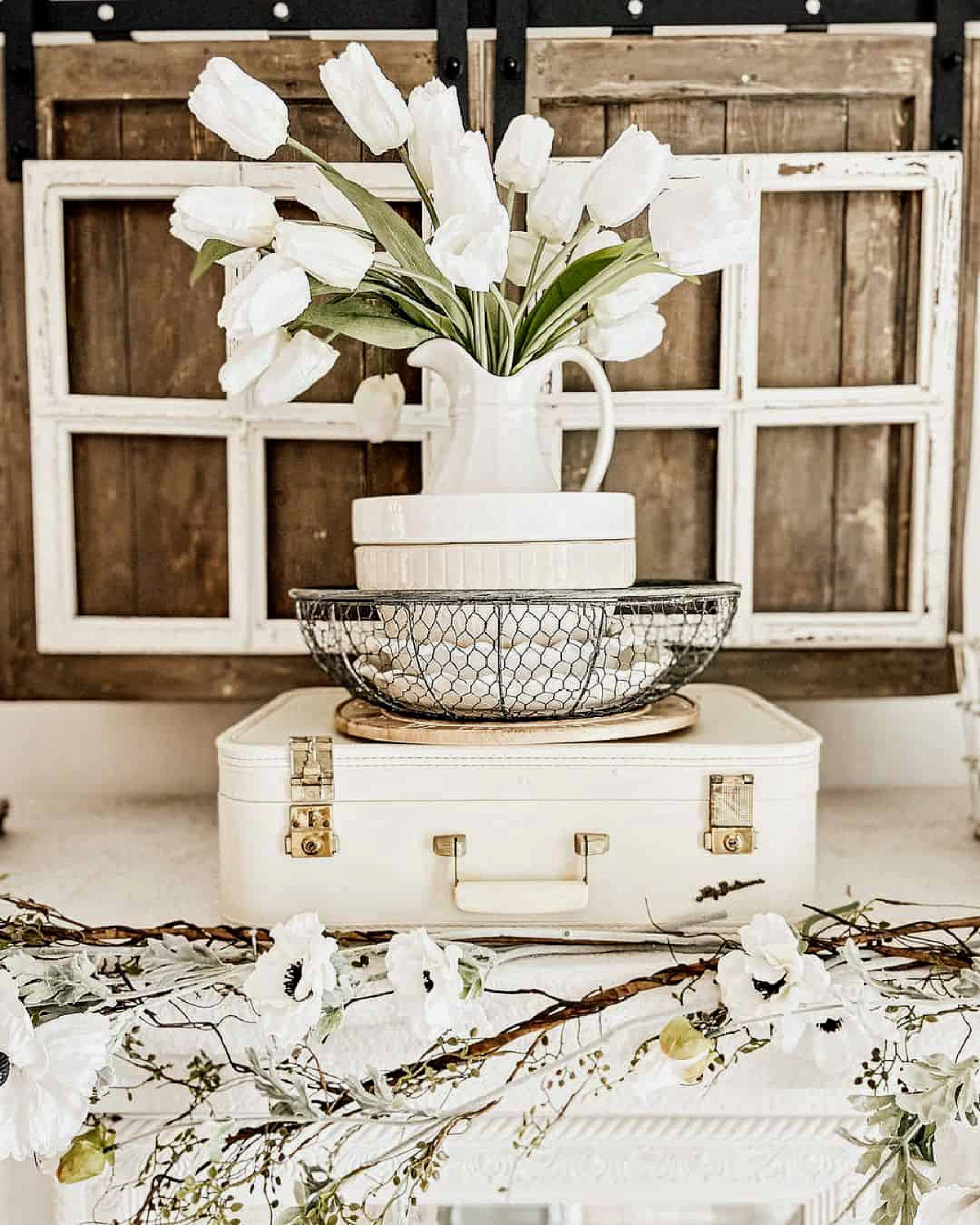 A neutral display with white pitcher with tulips.