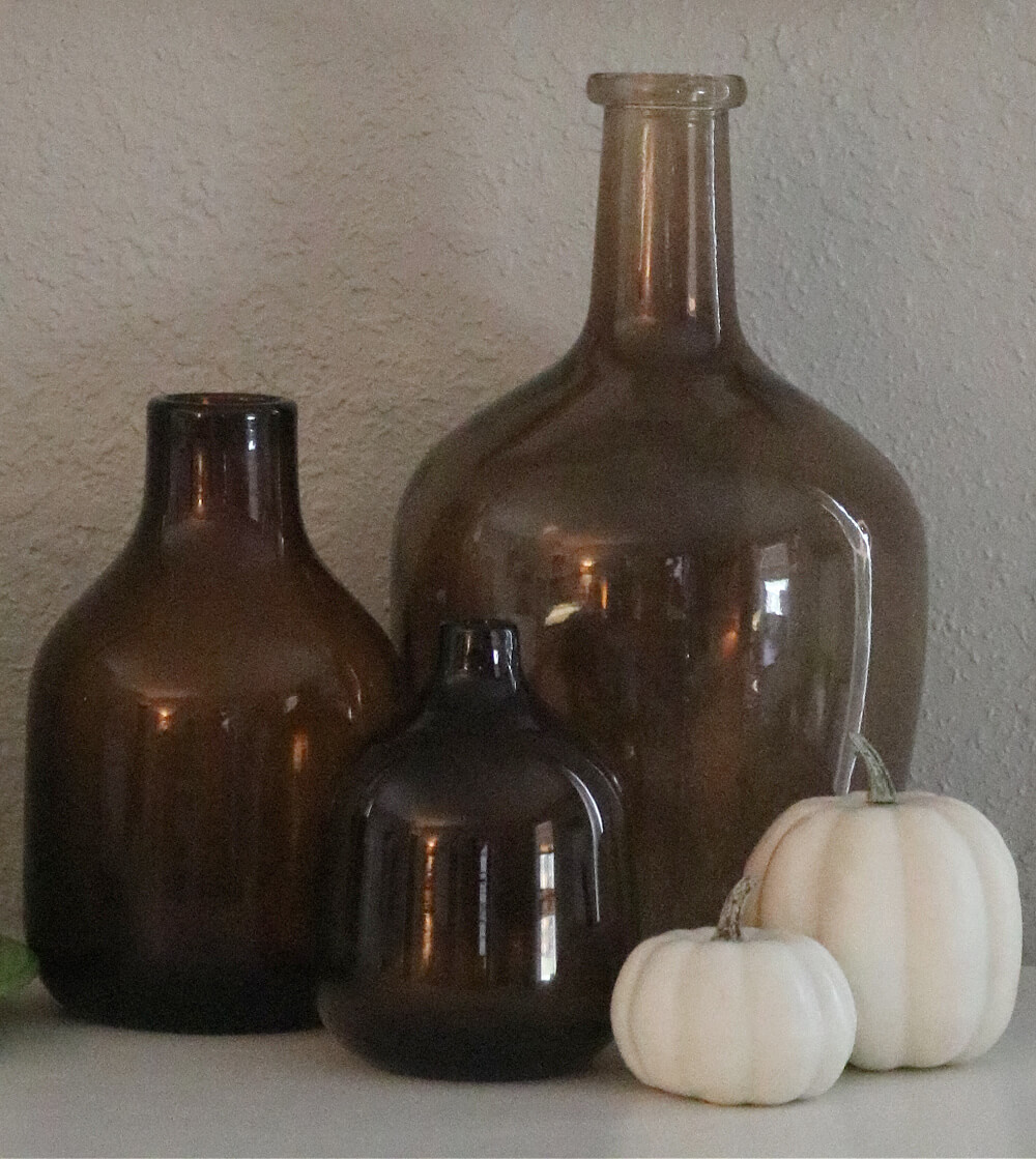 Amber glass bottles with beige faux mini pumpkins.
