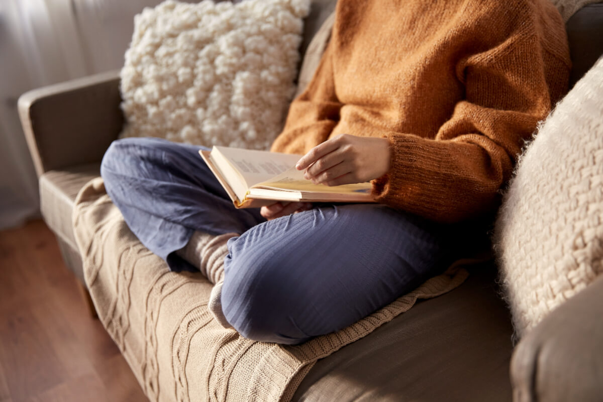 Woman reading book on her couch.