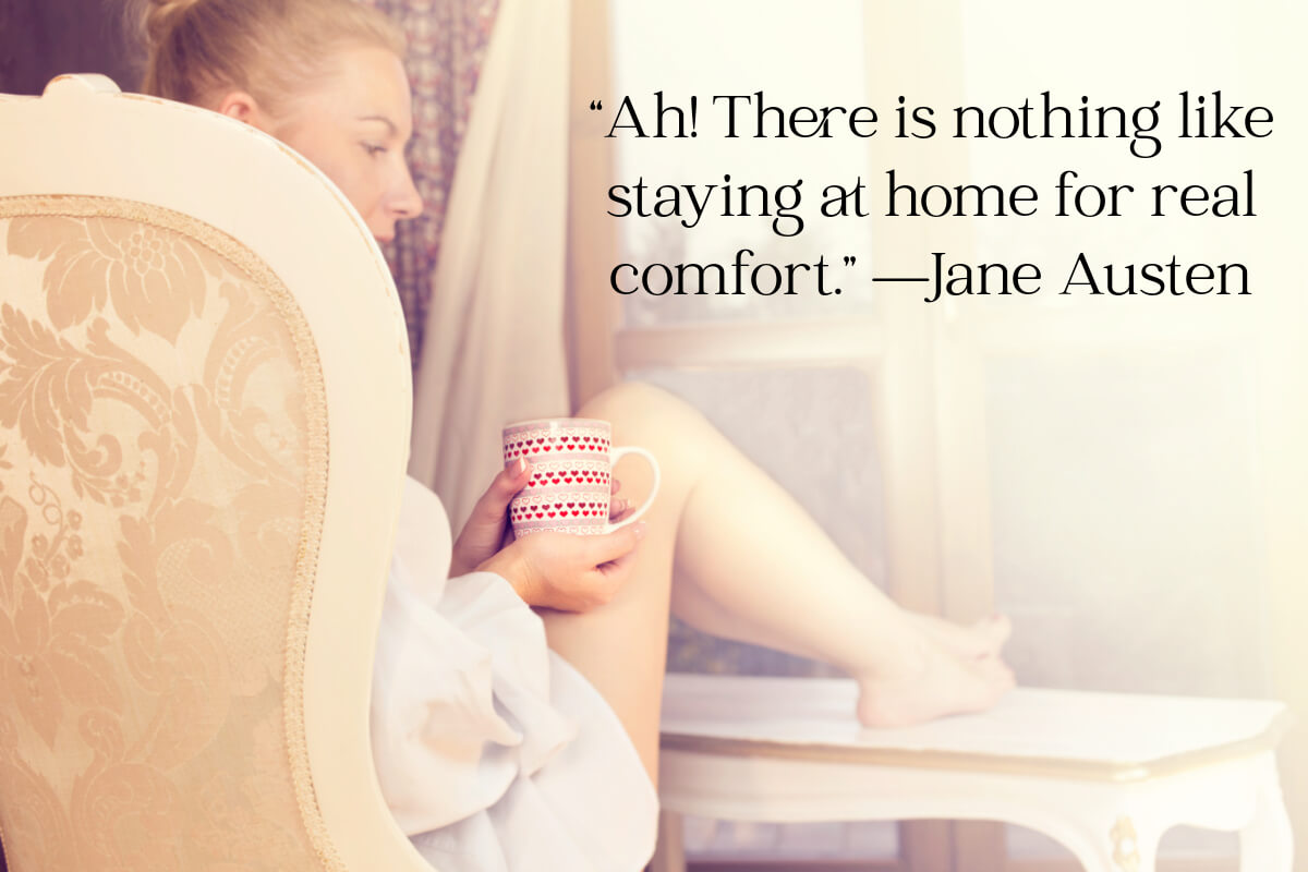 Woman sitting in a chair with a mug of something and her feet resting on a table.