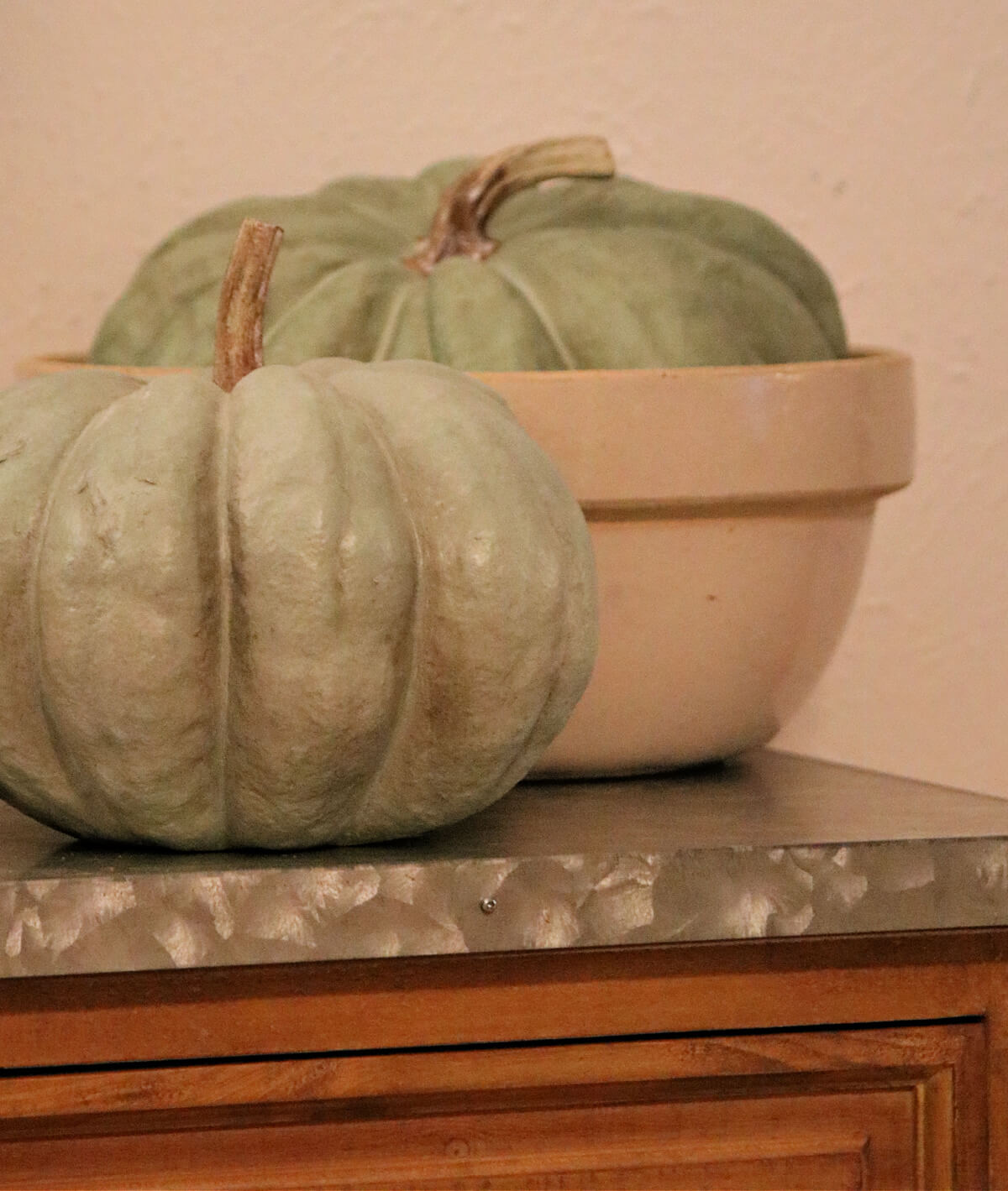 Faux green pumpkins, the largest one in a vintage bowl, for a fall bucket list for introverts.