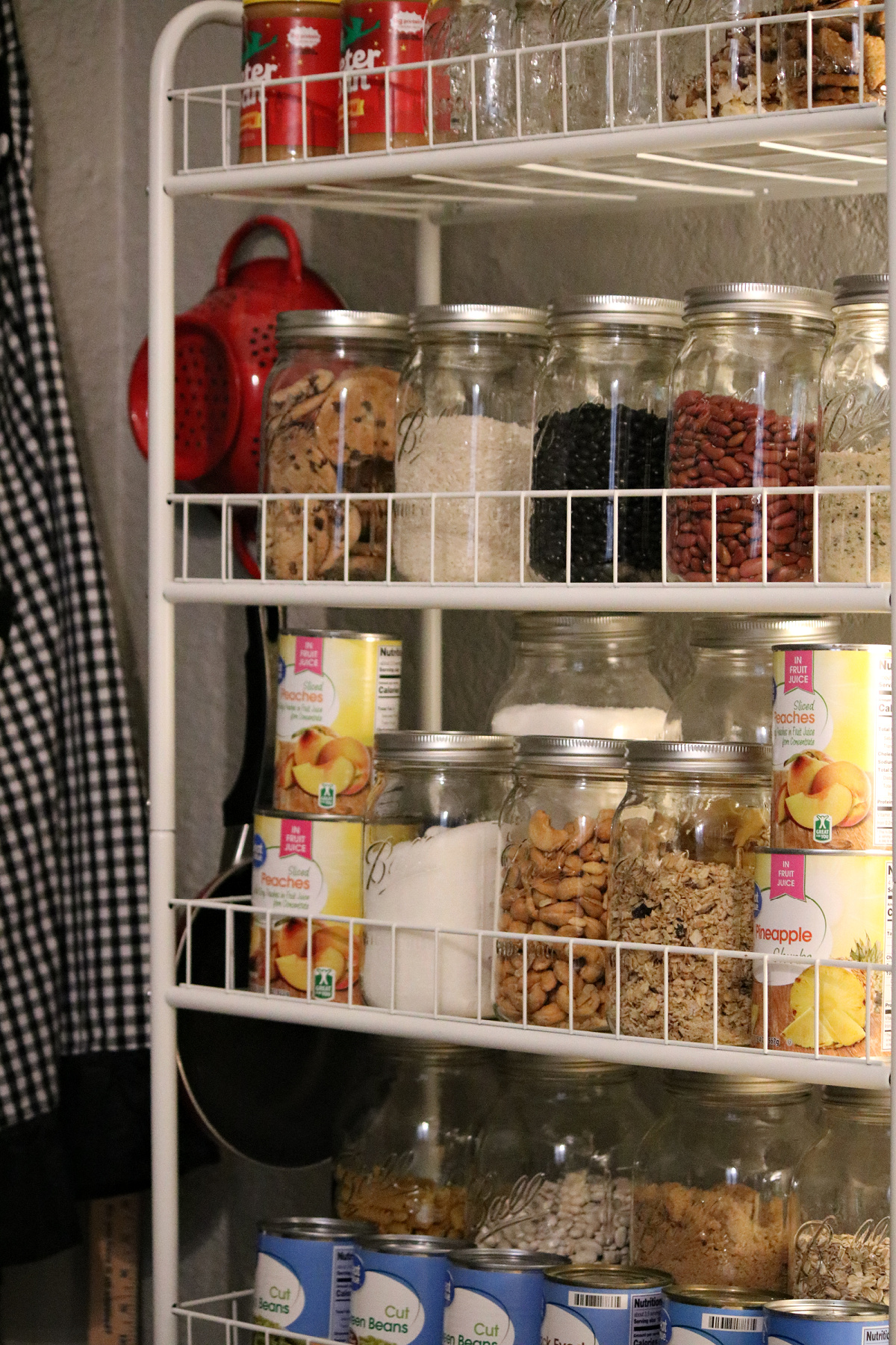 Organizing pantry food in clear glass Mason jars in my kitchen on rolling shelves.