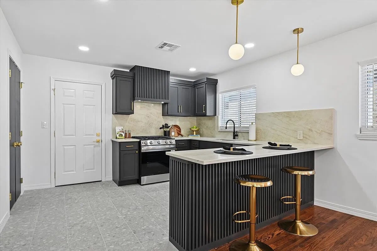 One view of the new kitchen with brown cabinets and gold bar stools.