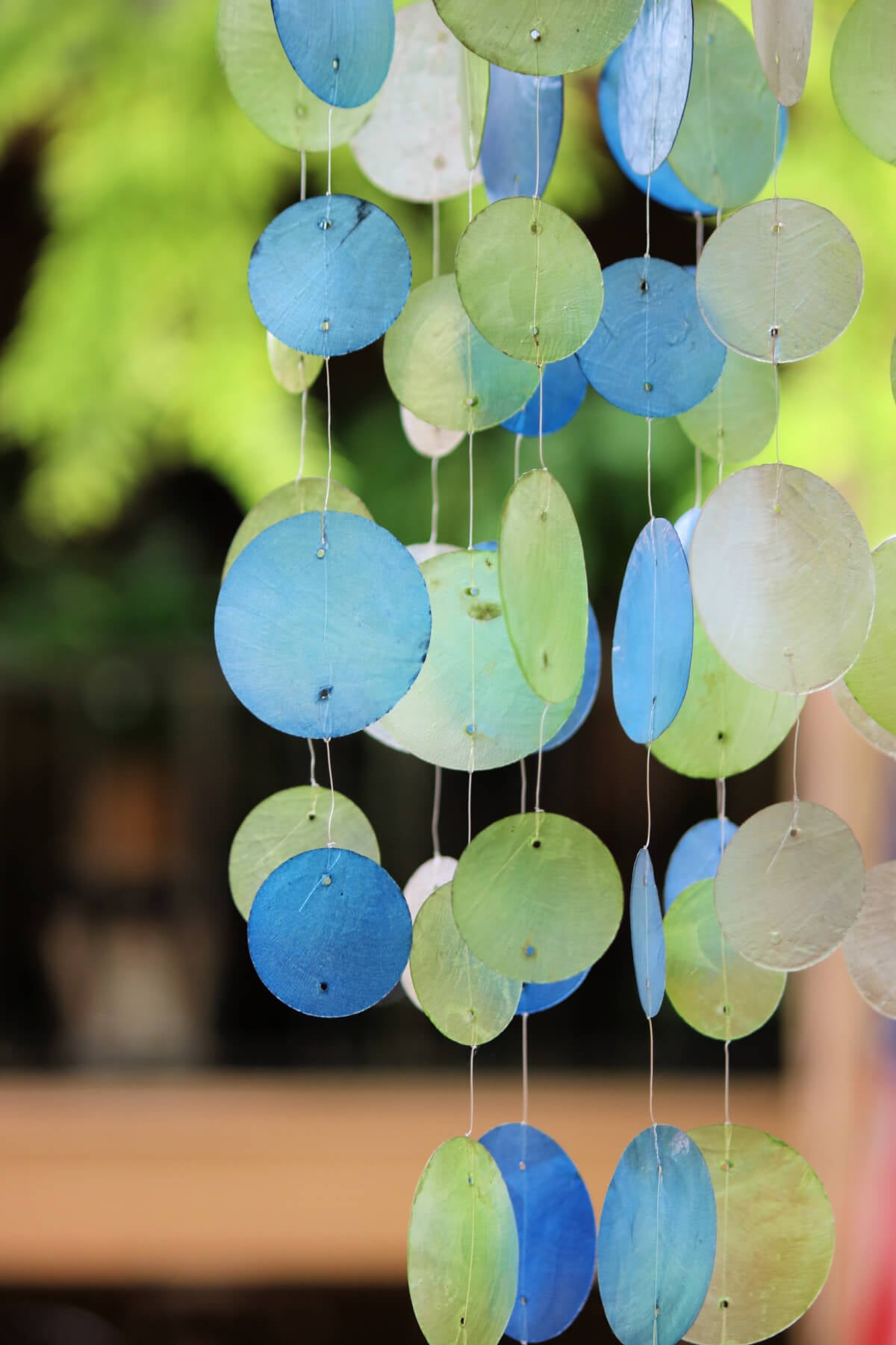 White, green, and blue wind chimes outdoors.